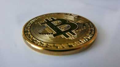 a gold bit coin sitting on top of a white table