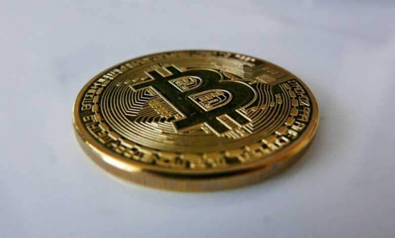 a gold bit coin sitting on top of a white table