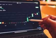 a person is holding a pencil in front of a laptop
